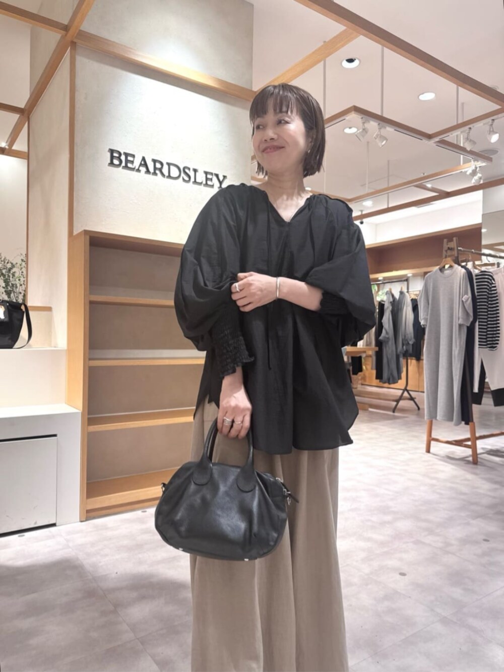 ブラック系のボストンバッグ、ベージュ系のその他パンツ、ブラック系のシャツ/ブラウスを着用したレディースの春コーディネートの7枚目の写真