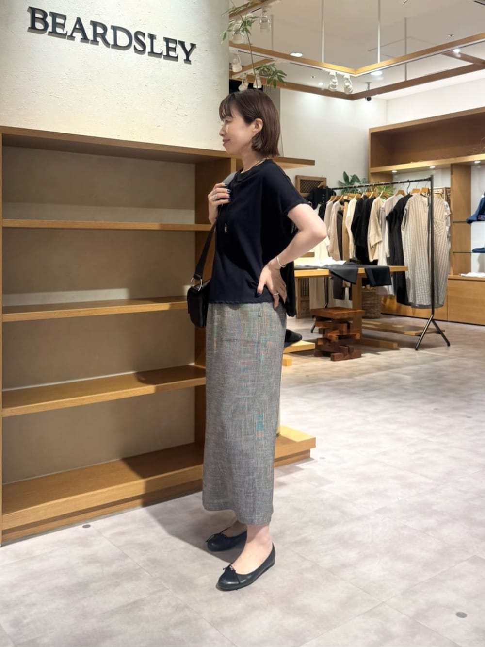 ブラック系のショルダーバッグ、ベージュ系のスカート、ゴールド系のネックレスを着用したレディースの春コーディネートの5枚目の写真