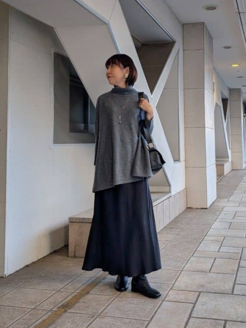 ブラック系のスカート、グレー系のニット/セーター、ブラック系のショルダーバッグを着用したレディースの冬コーディネートの2枚目の写真