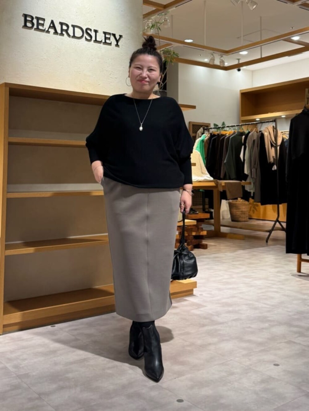 ブラック系のニット/セーター、ブラック系のブーツ、ブラウン系のスカートを着用したレディースの冬コーディネートの2枚目の写真