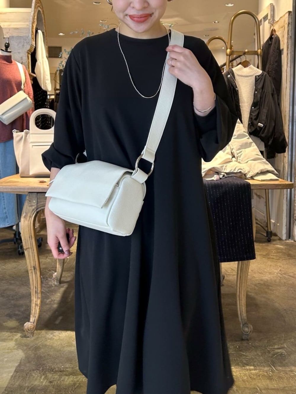 ホワイト系のショルダーバッグ、ブラック系のワンピースを着用したレディースの冬コーディネートの4枚目の写真