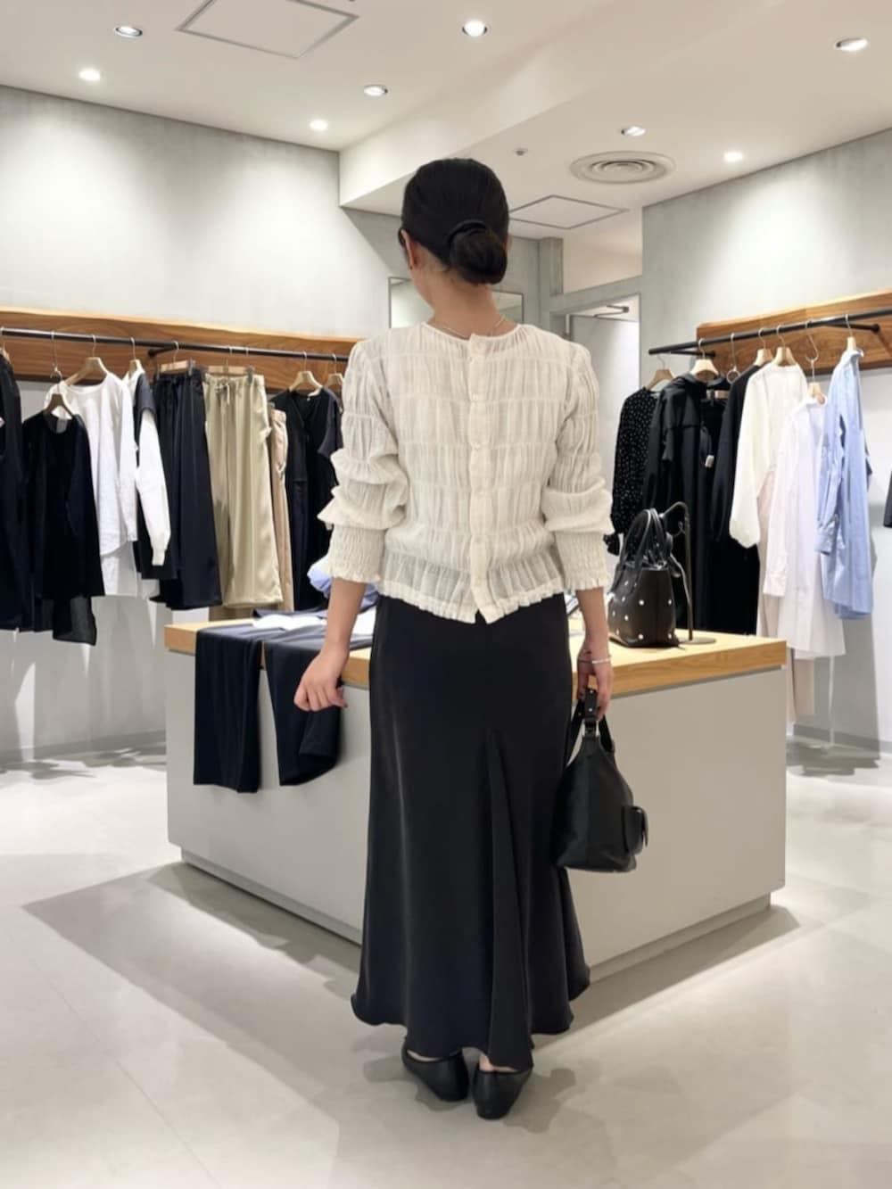 ブラック系のスカート、ブラック系のトートバッグ、ホワイト系のシャツ/ブラウスを着用したレディースの春コーディネートの7枚目の写真