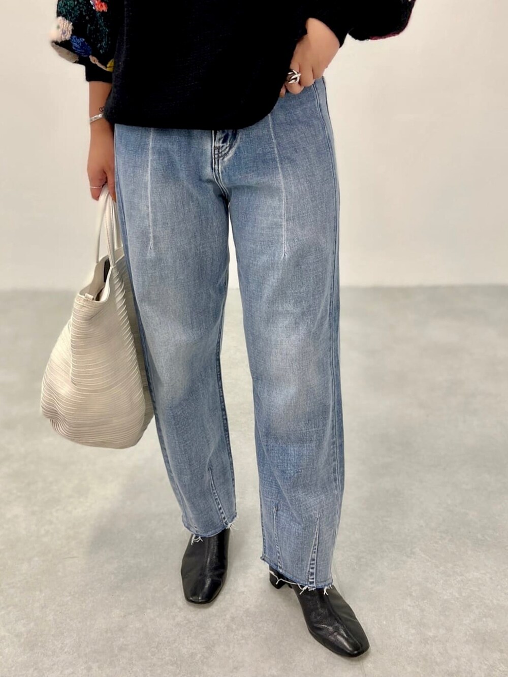 ブラック系のニット/セーター、ブルー系のデニムパンツを着用したレディースの夏コーディネートの4枚目の写真