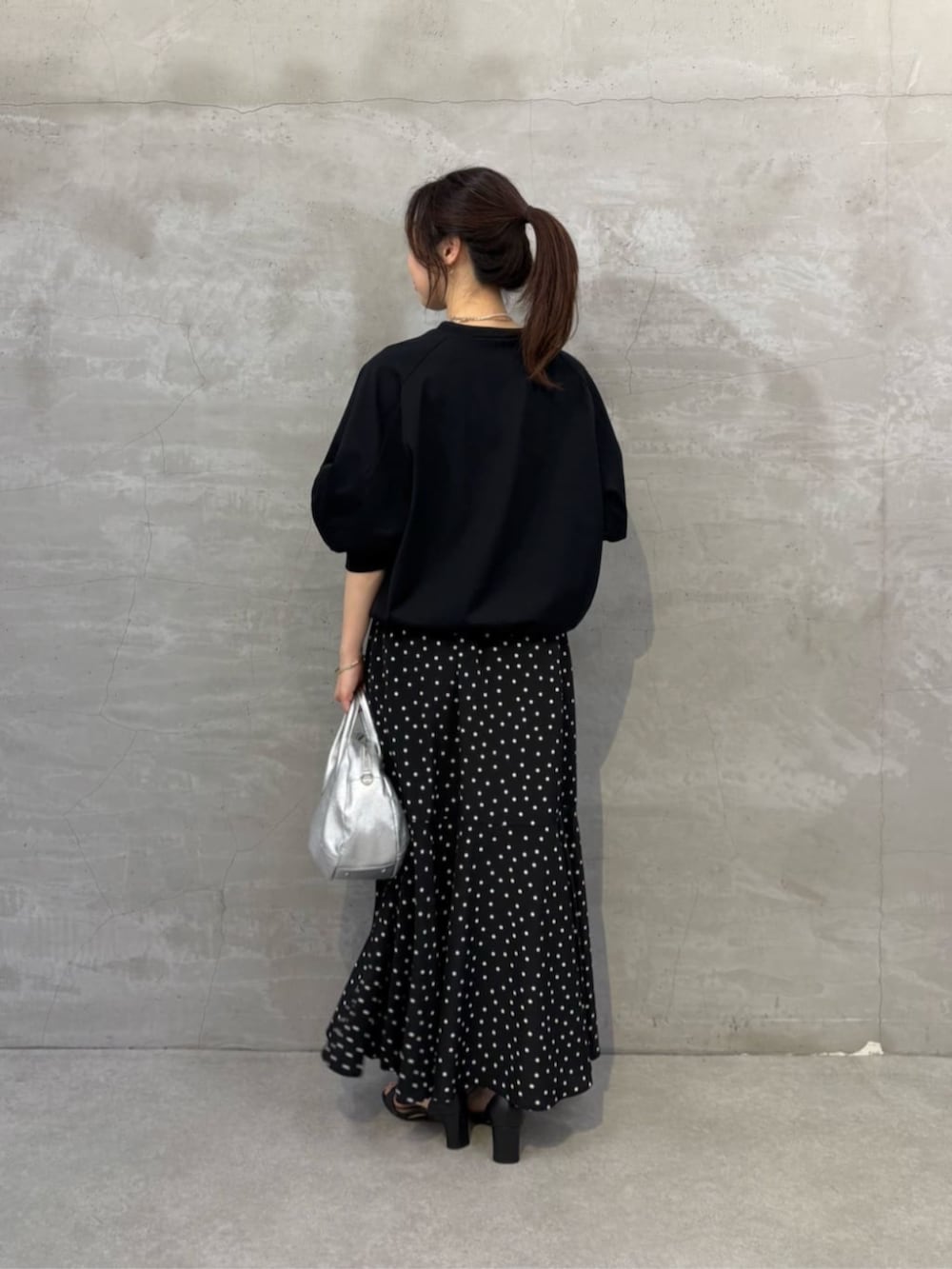 シルバー系のボストンバッグ、ブラック系のスカート、ブラック系のTシャツ/カットソーを着用したレディースの冬コーディネートの3枚目の写真