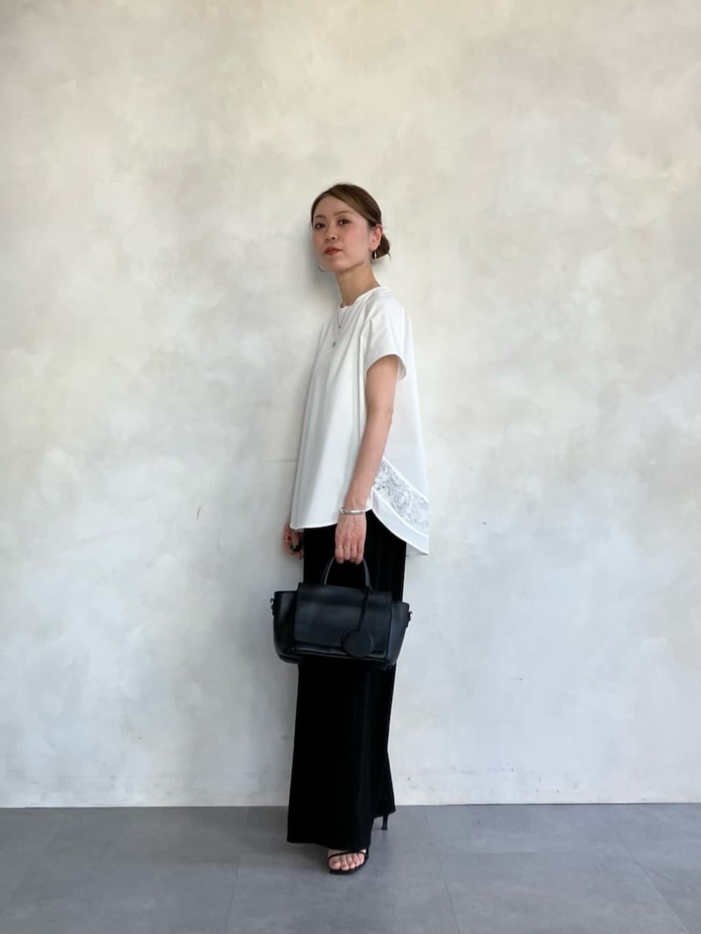 ブラック系のハンドバッグ、ホワイト系のTシャツ/カットソーを着用したレディースの春コーディネートの4枚目の写真