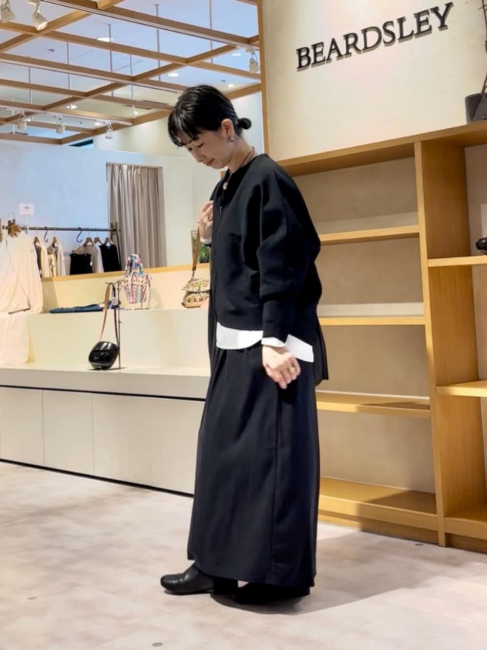 ブラック系のカーディガン/ボレロ、ブラック系のスカート、ブラック系のトートバッグを着用したレディースの秋コーディネートの3枚目の写真
