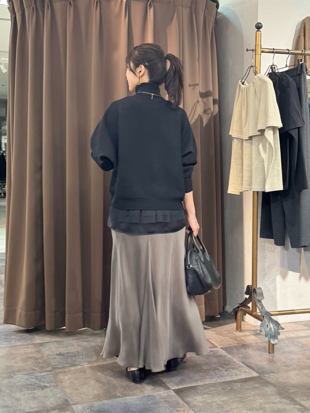 グリーン系のスカート、ブラック系のボストンバッグ、ブラック系のニット/セーターを着用したレディースの冬コーディネートの4枚目の写真