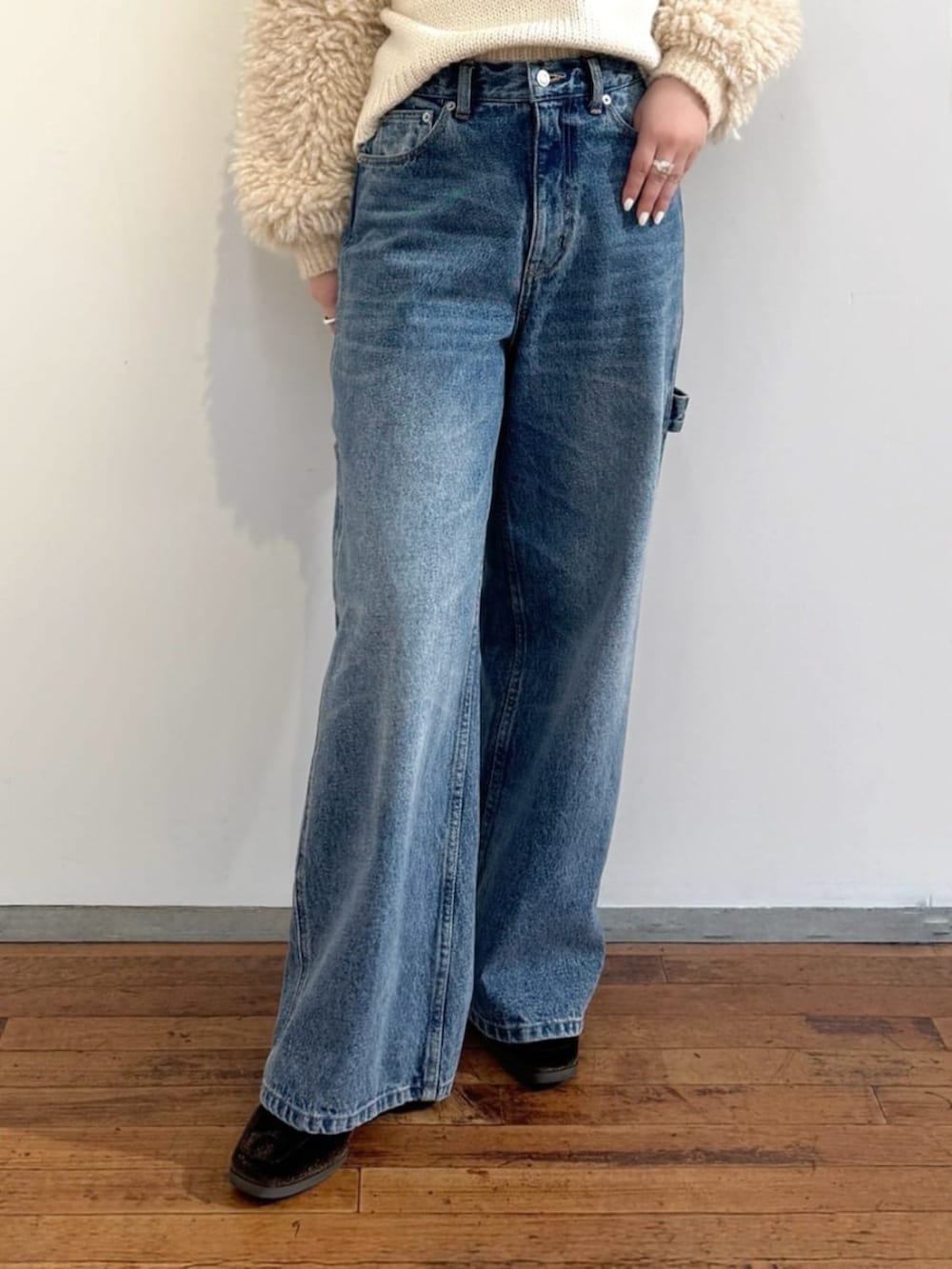 ブルー系のデニムパンツ、ホワイト系のニット/セーター、グリーン系のポーチを着用したレディースの秋コーディネートの6枚目の写真