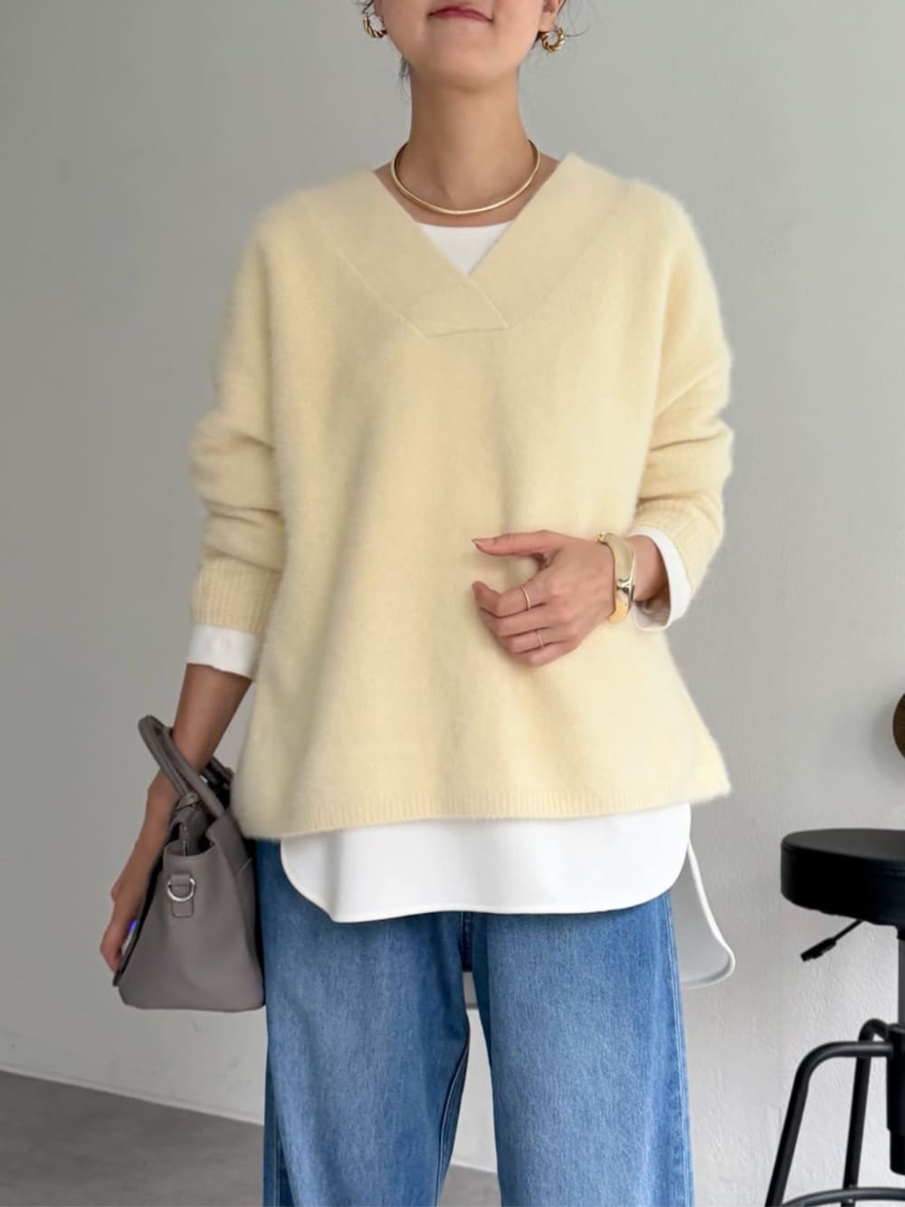 グレー系のハンドバッグ、ホワイト系のシャツ/ブラウス、イエロー系のニット/セーターを着用したレディースの秋コーディネートの3枚目の写真