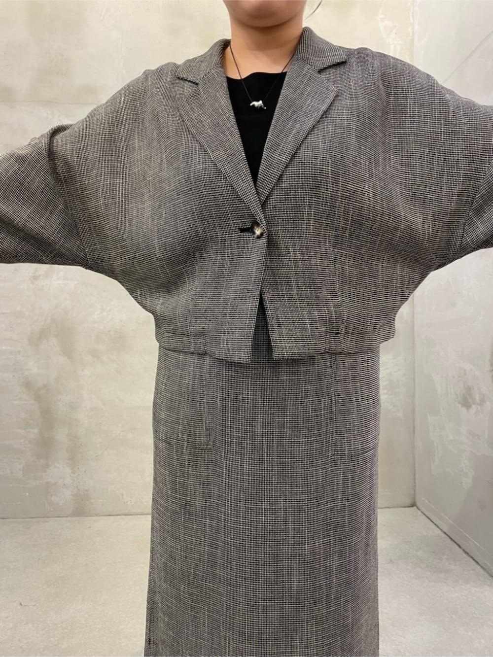 ブラック系のハンドバッグ、ベージュ系のテーラードジャケット、ベージュ系のスカートを着用したレディースの春コーディネートの5枚目の写真