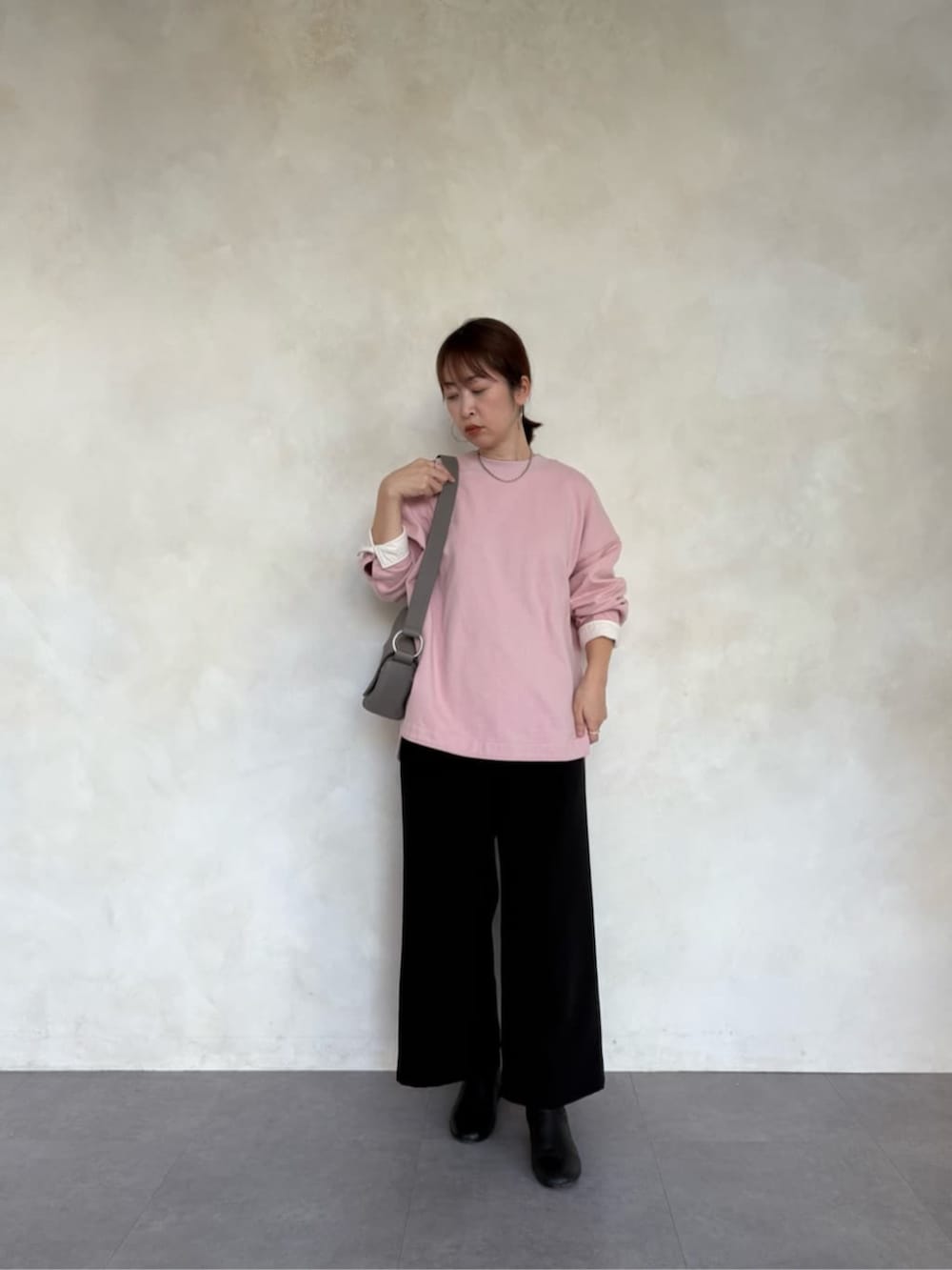 グレー系のショルダーバッグ、ピンク系のTシャツ/カットソー、ブラック系のその他パンツを着用したレディースの冬コーディネートの5枚目の写真