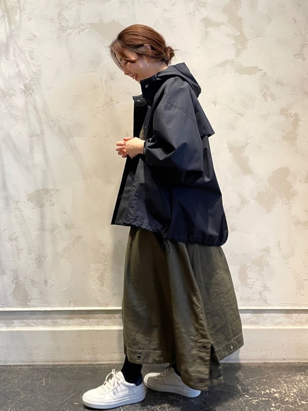 ブラック系のマウンテンパーカー、グリーン系のワンピース、ホワイト系のスニーカーを着用したレディースの春コーディネートの2枚目の写真