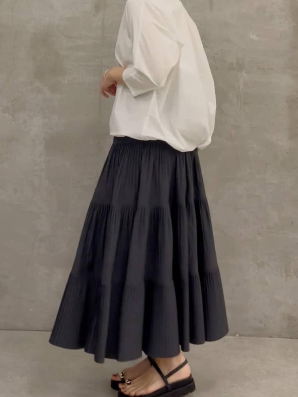 グレー系のスカート、ブラック系のショルダーバッグ、ホワイト系のシャツ/ブラウスを着用したレディースの春コーディネートの4枚目の写真