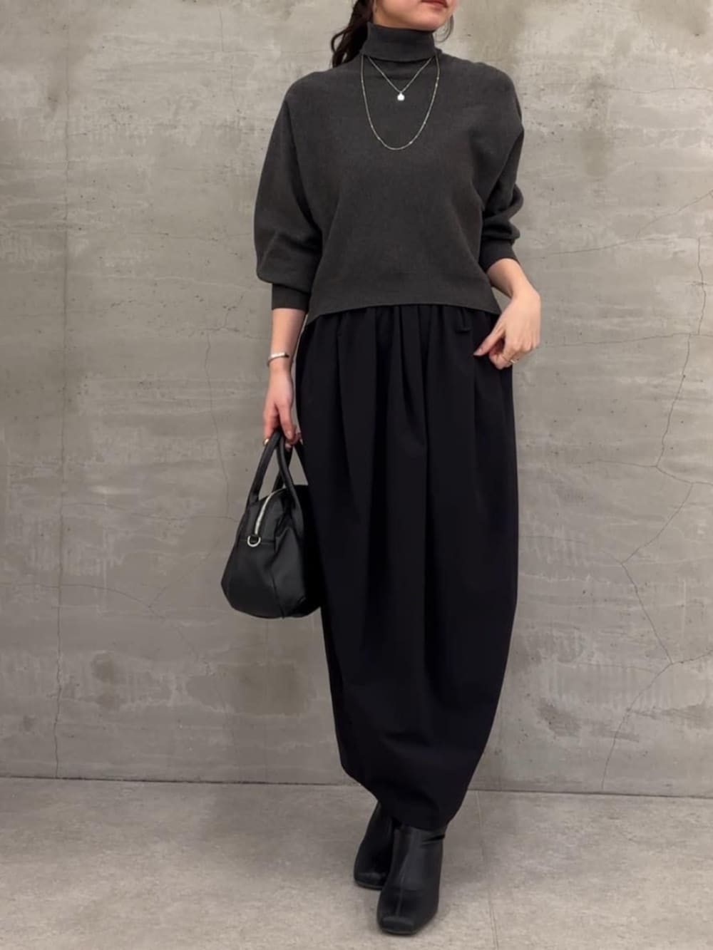 グレー系のニット/セーター、ブラック系のスカートを着用したレディースの冬コーディネートの3枚目の写真