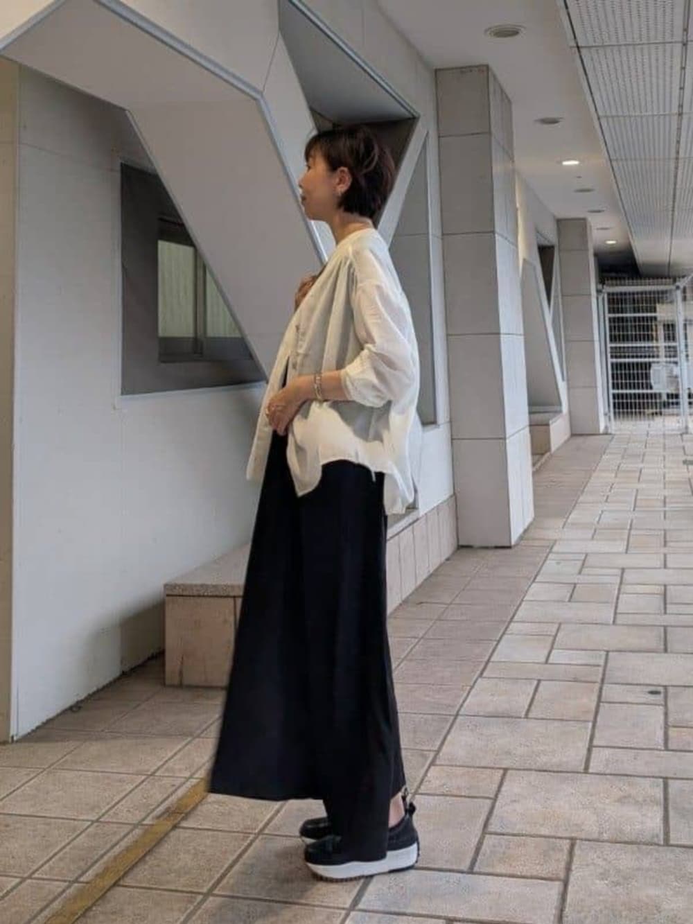 ホワイト系のシャツ/ブラウス、ブラック系のワンピース、ブラック系のスニーカーを着用したレディースの夏コーディネートの2枚目の写真