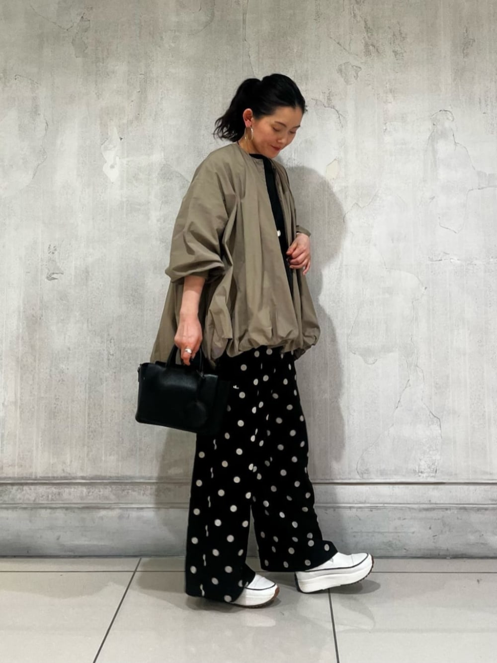 ブラック系のハンドバッグ、ブラック系のその他パンツ、ブラウン系のブルゾンを着用したレディースの春コーディネートの2枚目の写真