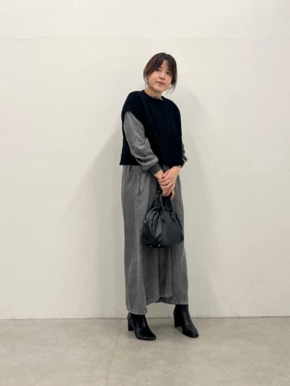 グレー系のワンピース、ブラック系のベストを着用したレディースの秋コーディネートの8枚目の写真