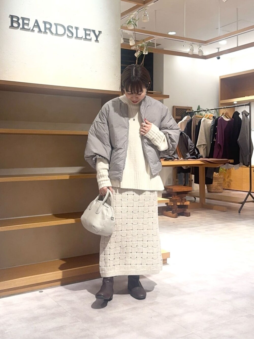 グレー系のボストンバッグ、ベージュ系のスカート、ブラウン系のダウンジャケット/コートを着用したレディースの冬コーディネートの3枚目の写真