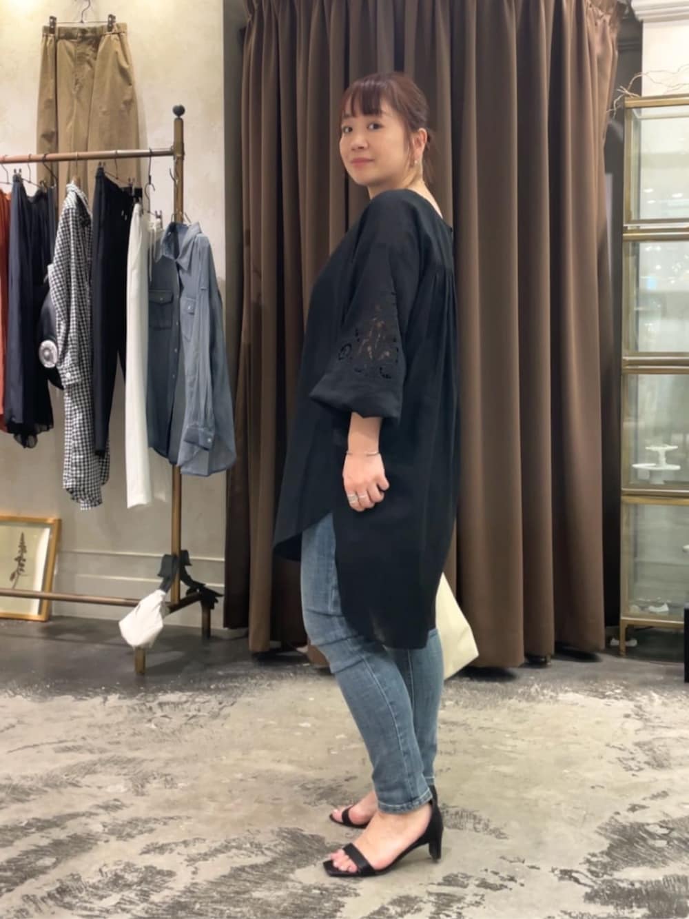 ブルー系のデニムパンツ、ホワイト系のショルダーバッグ、ブラック系のシャツ/ブラウスを着用したレディースの春コーディネートの5枚目の写真