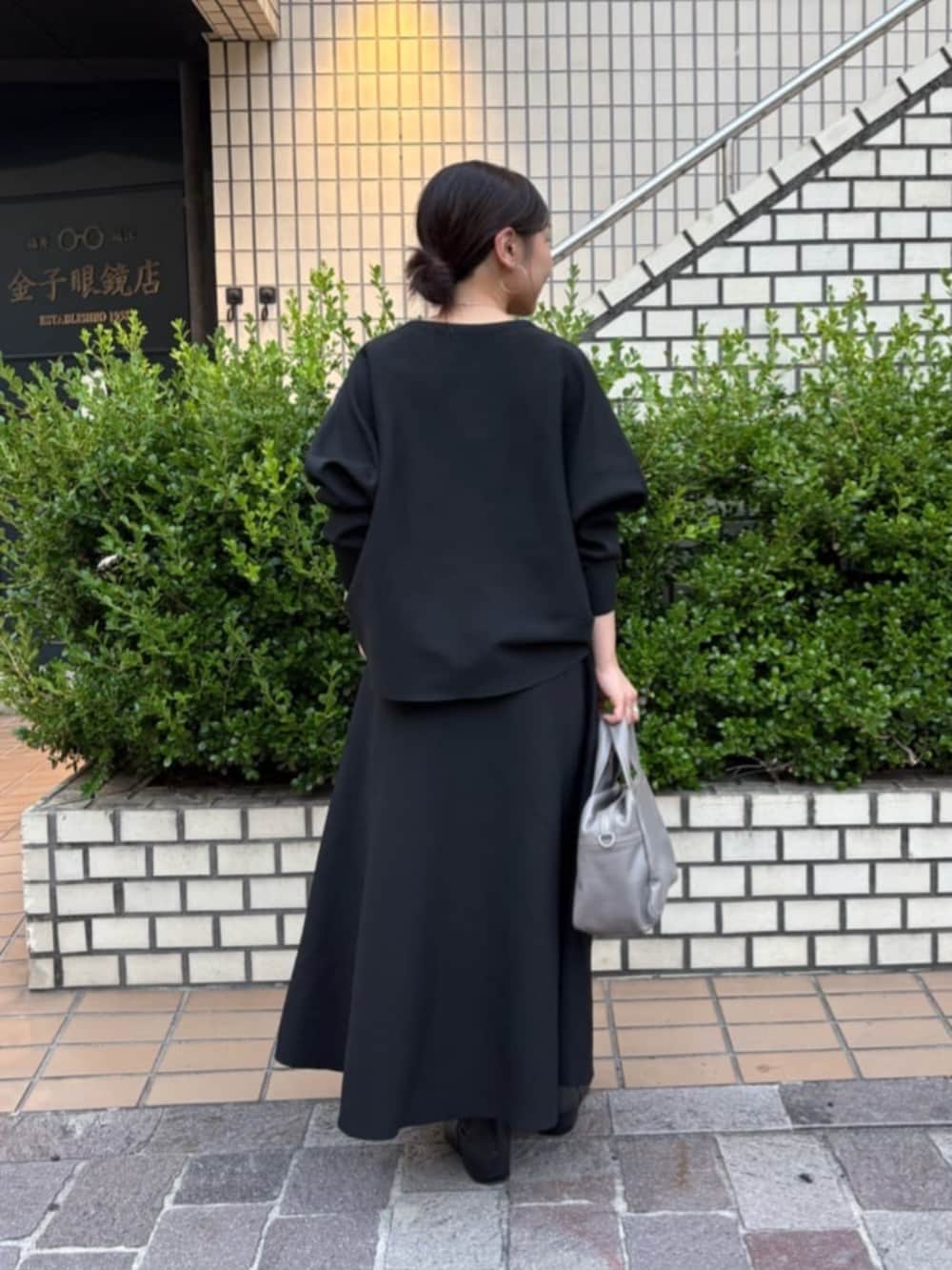 グレー系のボストンバッグ、ブラック系のスカート、ブラック系のカーディガン/ボレロを着用したレディースの秋コーディネートの7枚目の写真