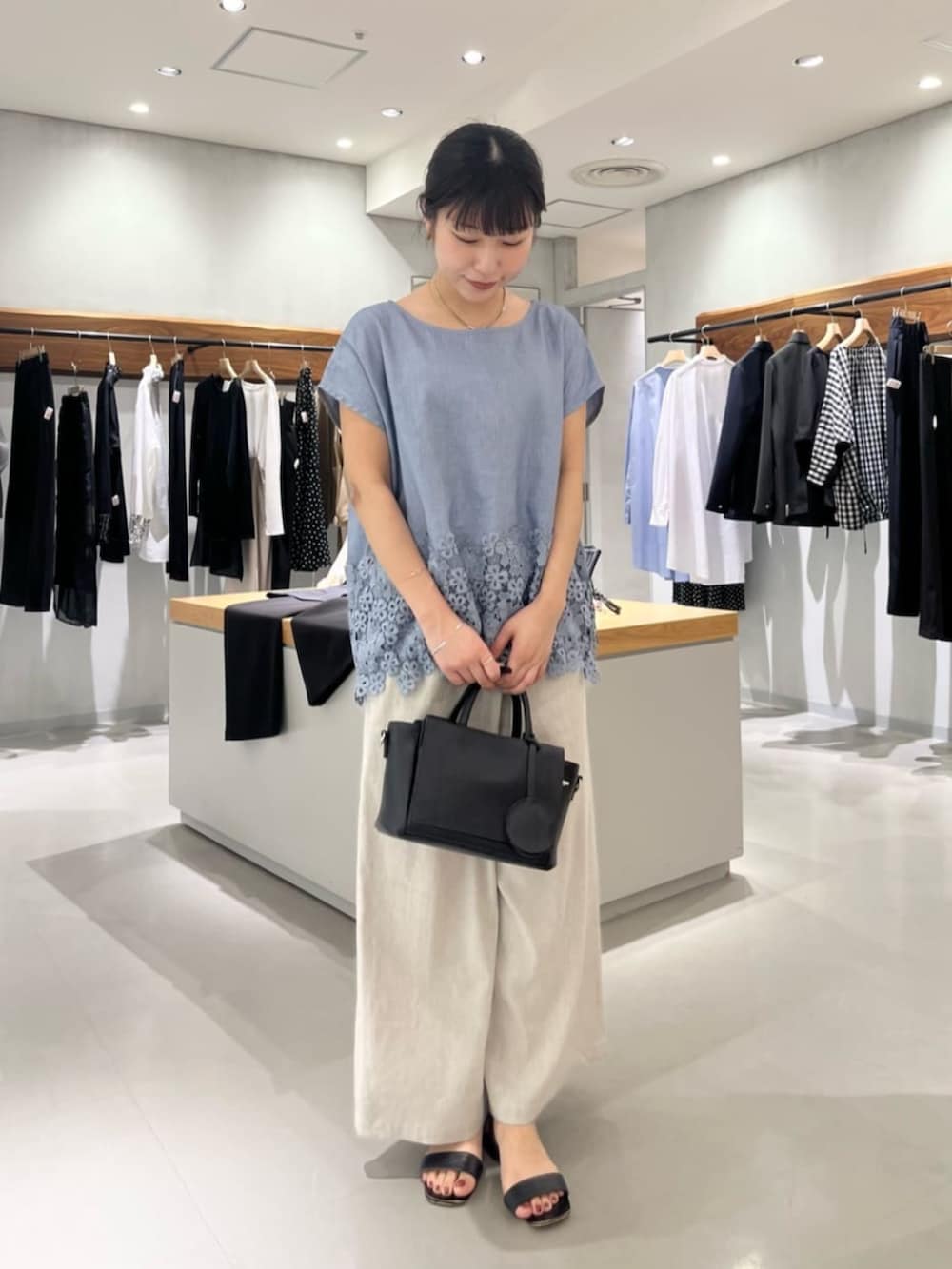 ブラック系のハンドバッグ、ベージュ系のその他パンツ、ブルー系のシャツ/ブラウスを着用したレディースの夏コーディネートの7枚目の写真