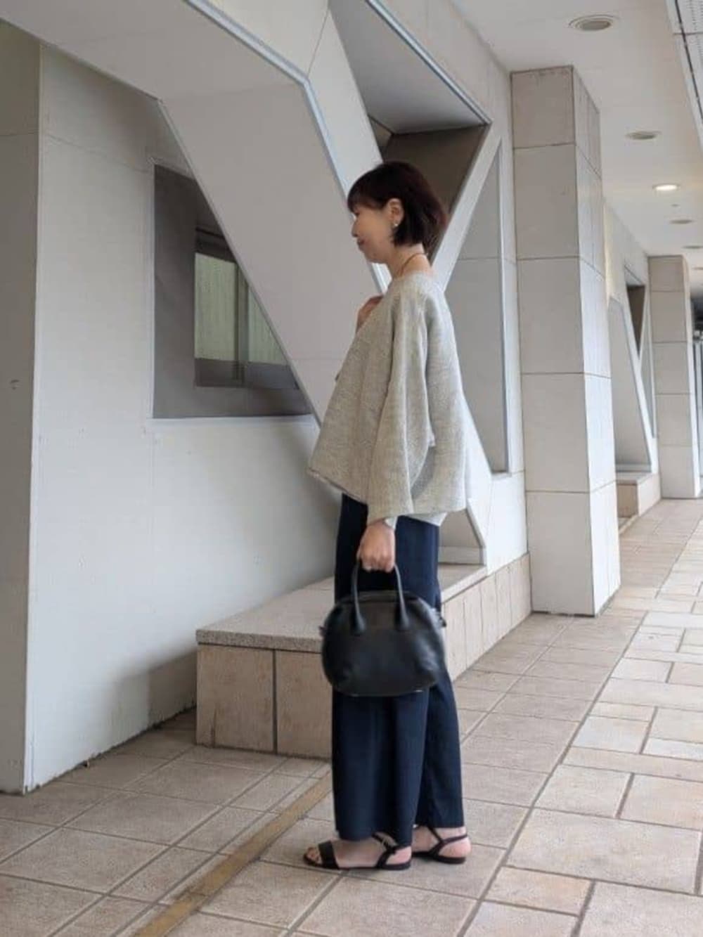 ブルー系のその他パンツ、ブラック系のボストンバッグ、グレー系のニット/セーターを着用したレディースの冬コーディネートの2枚目の写真