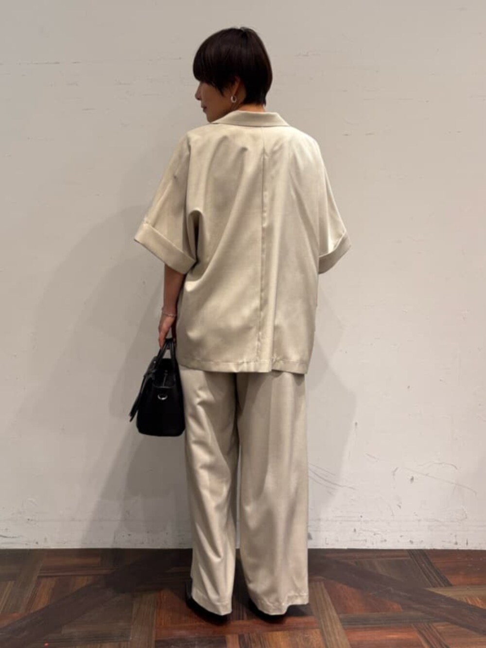 ブラック系のハンドバッグ、ベージュ系のテーラードジャケット、ベージュ系のその他パンツを着用したレディースの春コーディネートの3枚目の写真