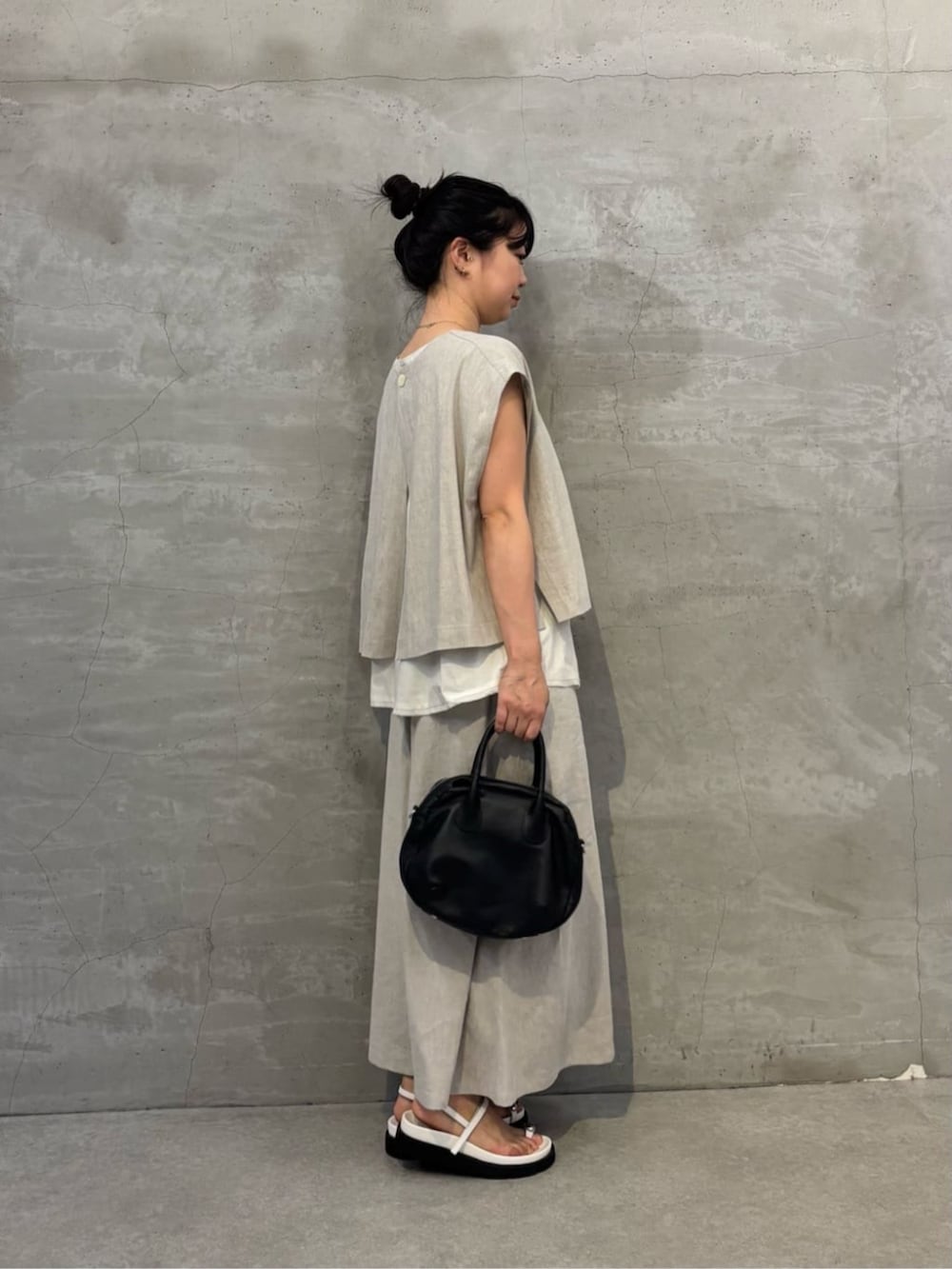 ブラック系のボストンバッグ、ホワイト系のサンダル、ホワイト系のシャツ/ブラウスを着用したレディースの春コーディネートの2枚目の写真