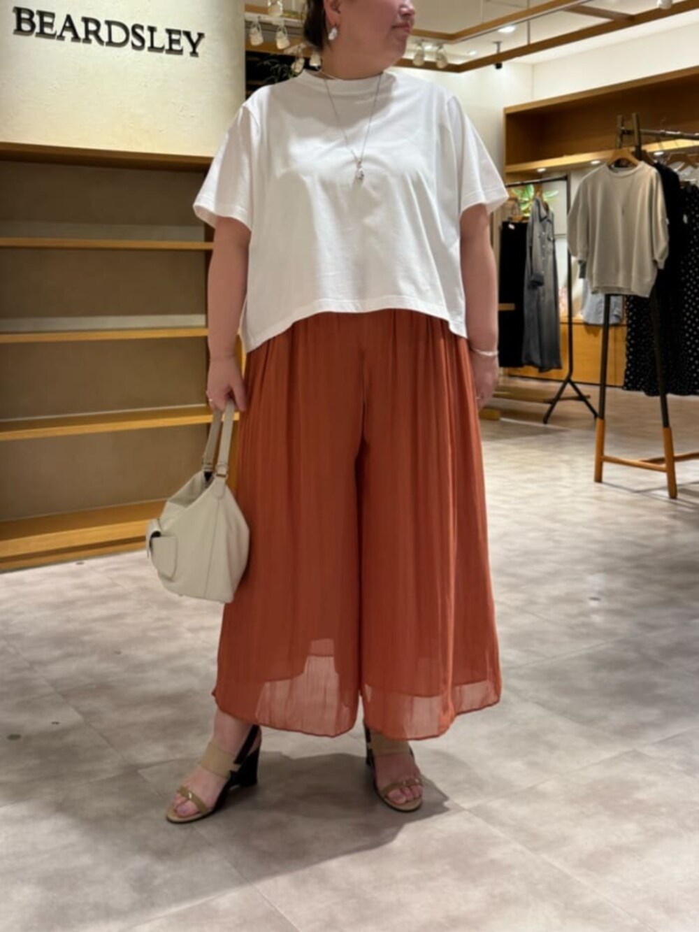 ホワイト系のトートバッグ、オレンジ系のその他パンツ、ホワイト系のTシャツ/カットソーを着用したレディースの春コーディネートの7枚目の写真