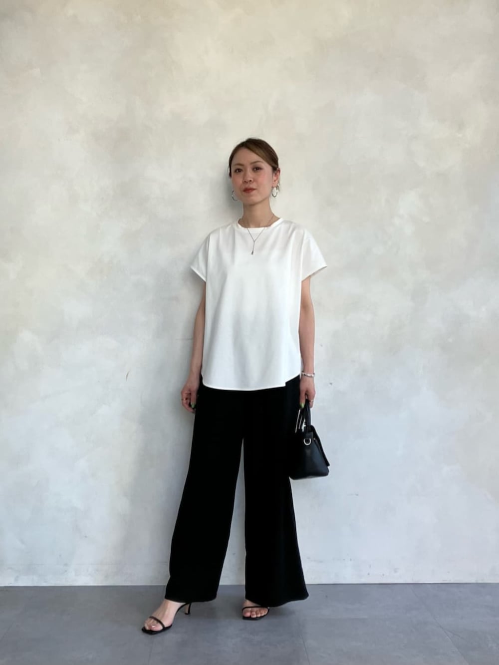 ブラック系のハンドバッグ、ホワイト系のTシャツ/カットソーを着用したレディースの春コーディネートの7枚目の写真