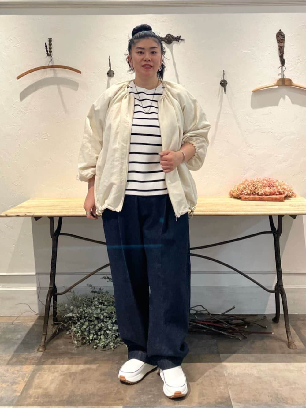 ホワイト系のノーカラージャケット、ホワイト系のニット/セーター、ブルー系のデニムパンツを着用したレディースの冬コーディネートの3枚目の写真