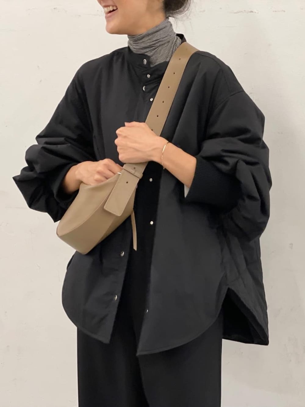 ブラック系のノーカラーコート、ベージュ系のトートバッグ、ブラック系のつなぎ/オールインワンを着用したレディースの秋コーディネートの2枚目の写真