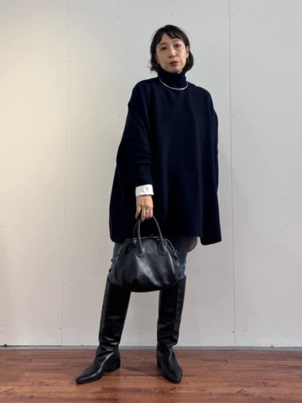 ブルー系のデニムパンツ、ブラック系のトートバッグ、ブルー系のニット/セーターを着用したレディースの秋コーディネートの2枚目の写真
