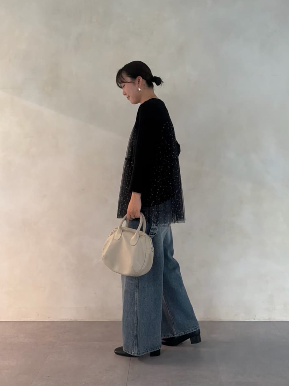 グレー系のボストンバッグ、ブラック系のTシャツ/カットソー、ブルー系のデニムパンツを着用したレディースの夏コーディネートの2枚目の写真