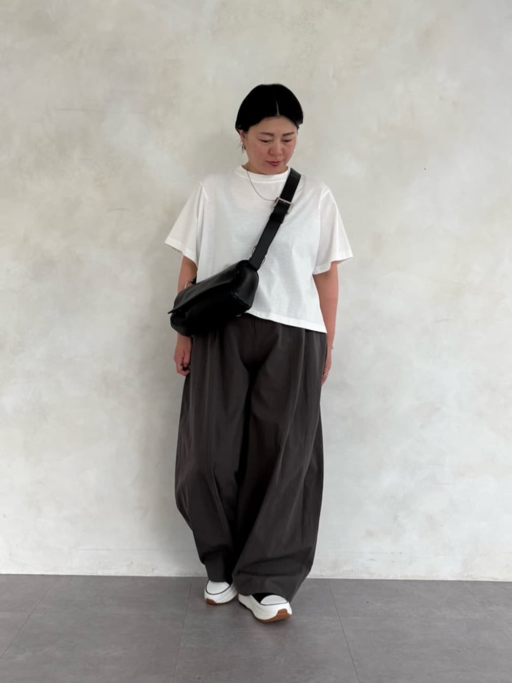 ブラック系のショルダーバッグ、グレー系のその他パンツ、ホワイト系のTシャツ/カットソーを着用したレディースの春コーディネートの2枚目の写真