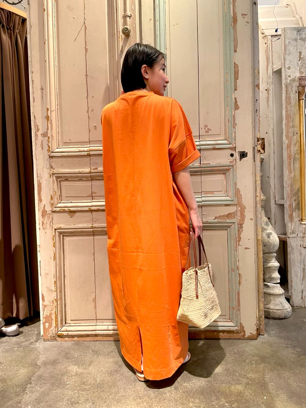 オレンジ系のTシャツ/カットソー、ホワイト系のかごバッグ、ホワイト系のサンダルを着用したレディースの春コーディネートの3枚目の写真