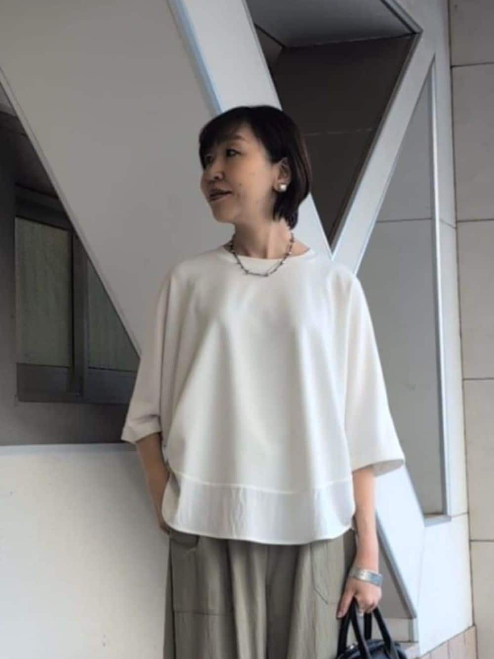 ブラック系のボストンバッグ、グリーン系のその他パンツ、ホワイト系のTシャツ/カットソーを着用したレディースの春コーディネートの6枚目の写真