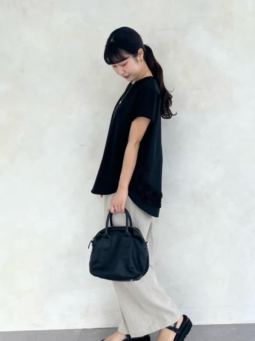 ベージュ系のその他パンツ、ブラック系のTシャツ/カットソー、ブラック系のサンダルを着用したレディースの春コーディネートの7枚目の写真