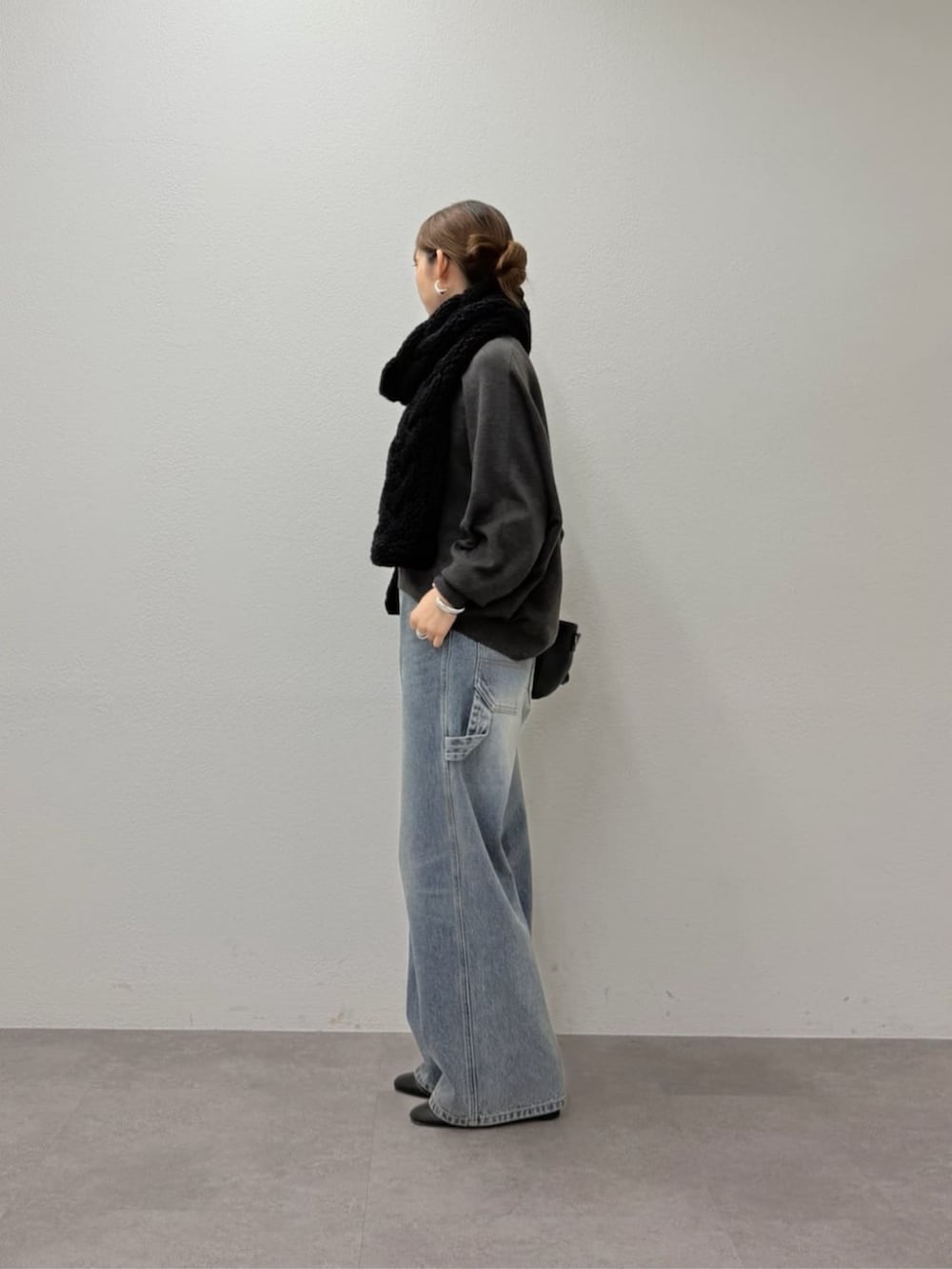 グレー系のニット/セーター、ブルー系のデニムパンツ、ブラック系のマフラーを着用したレディースの秋コーディネートの4枚目の写真