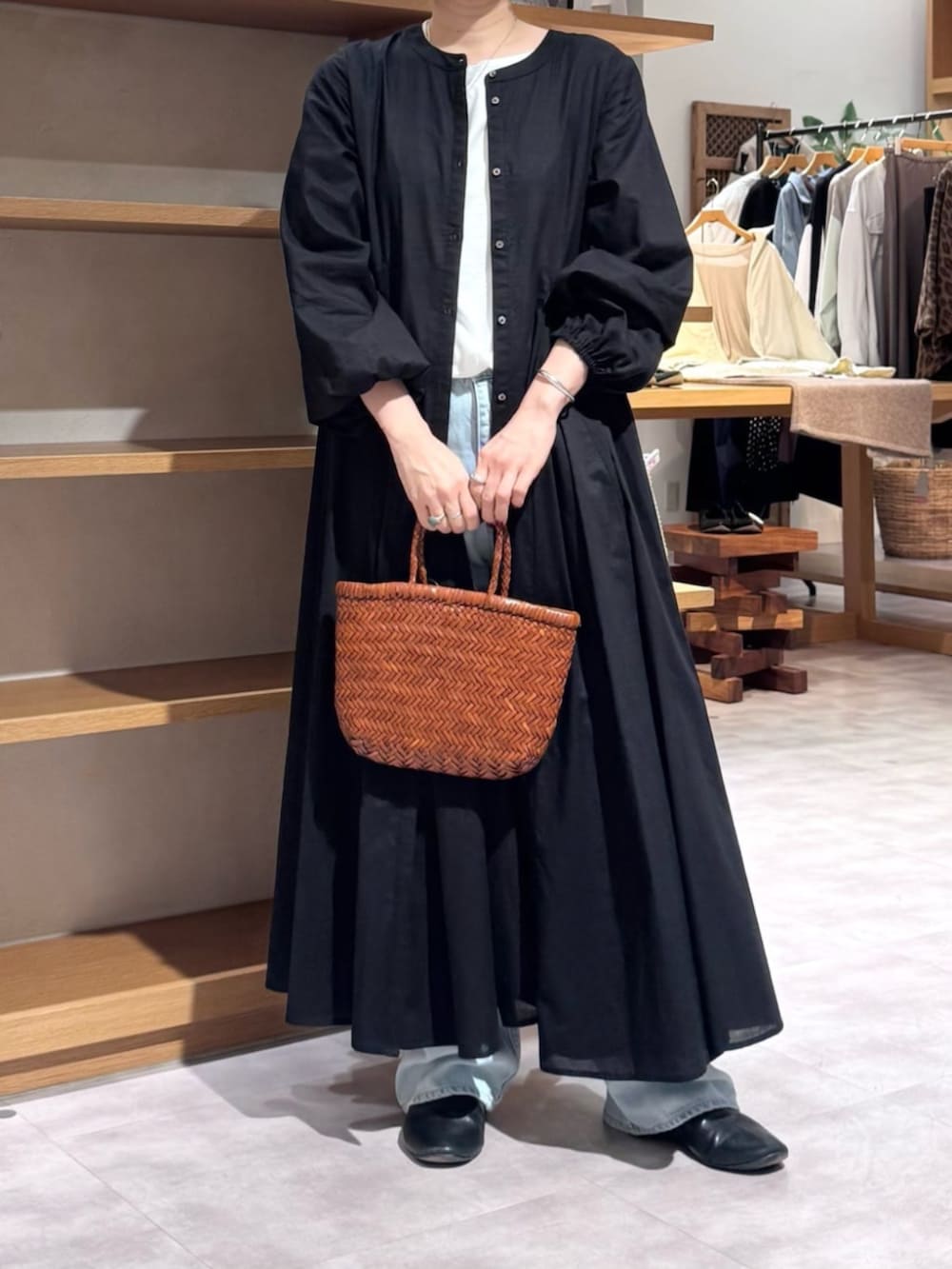 ブルー系のデニムパンツ、イエロー系のトートバッグ、ブラック系のワンピースを着用したレディースの冬コーディネートの3枚目の写真