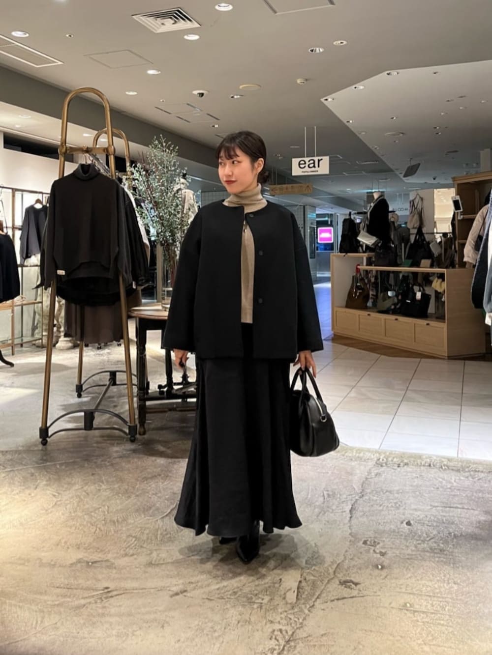 ブラック系のボストンバッグ、ブラック系のノーカラーコートを着用したレディースの冬コーディネートの2枚目の写真