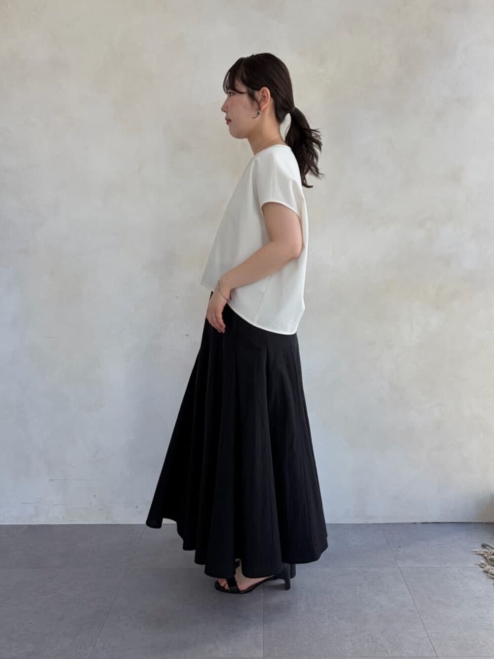 ブラック系のハンドバッグ、ホワイト系のシャツ/ブラウス、ブラック系のスカートを着用したレディースの春コーディネートの2枚目の写真