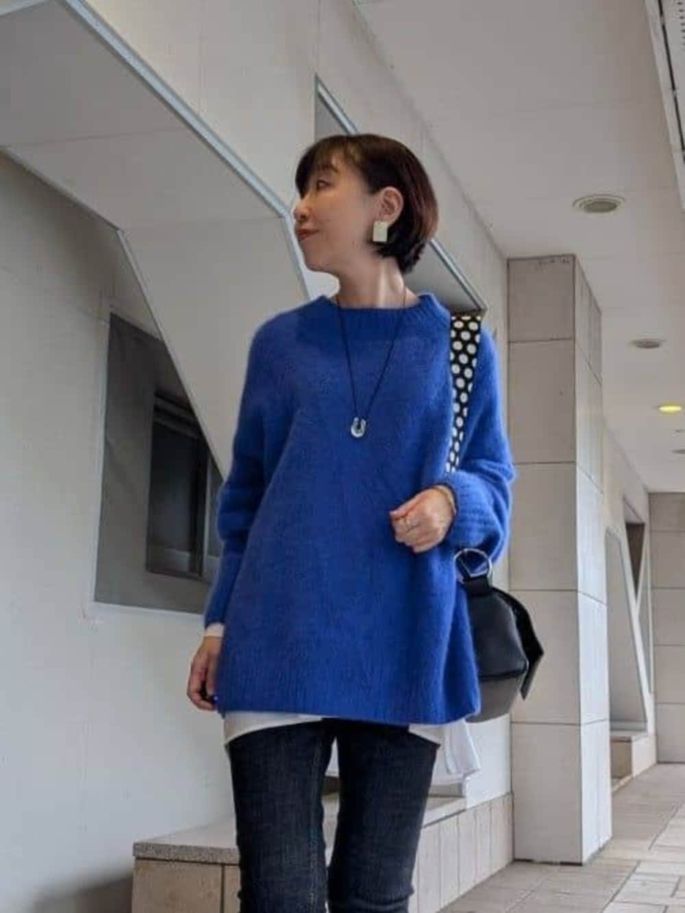 ホワイト系のTシャツ/カットソー、ホワイト系のスニーカー、ブルー系のニット/セーターを着用したレディースの冬コーディネートの7枚目の写真