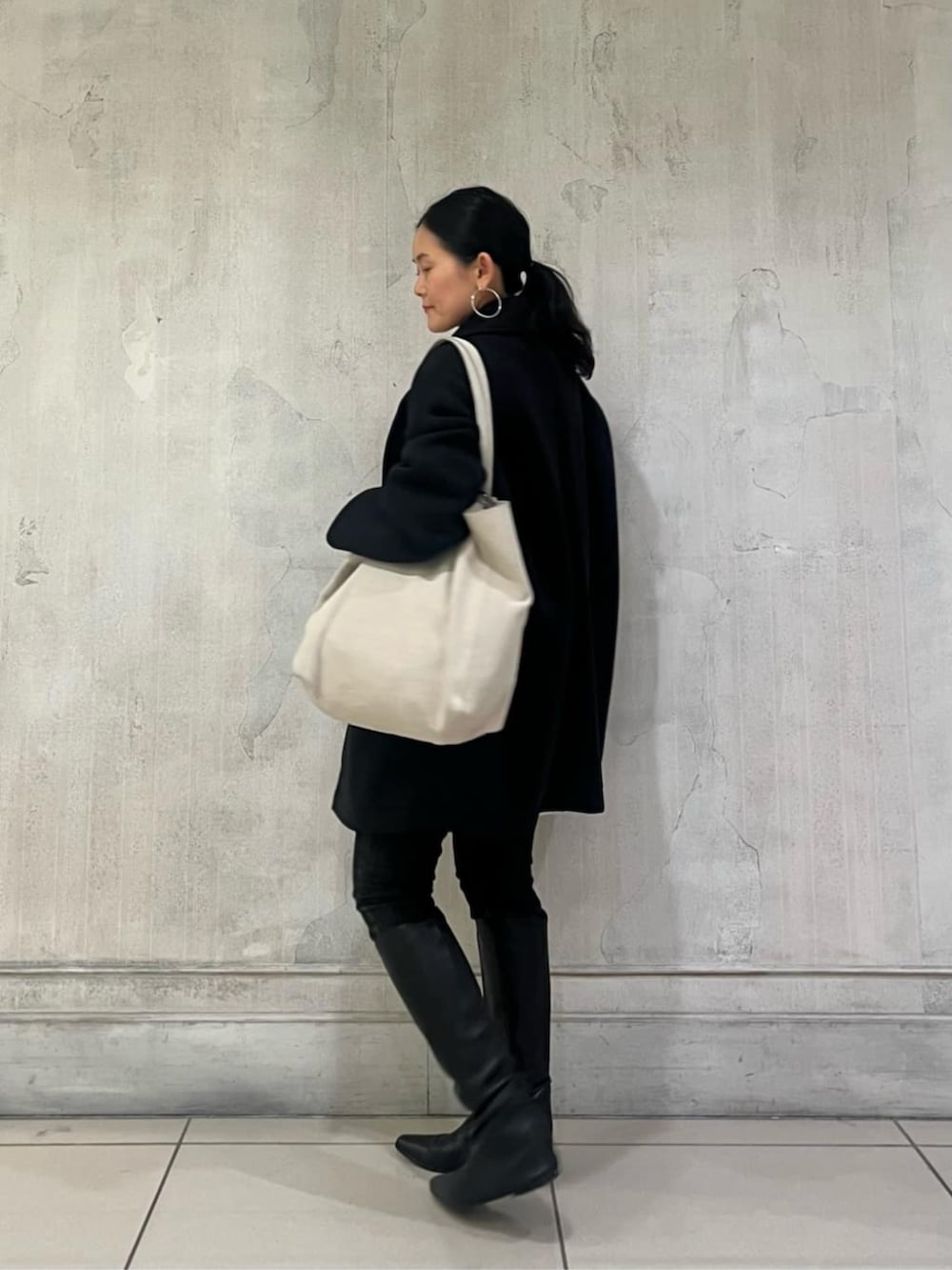 ブルー系のTシャツ/カットソー、ブラック系のデニムパンツ、ブラック系のピーコートを着用したレディースの冬コーディネートの5枚目の写真