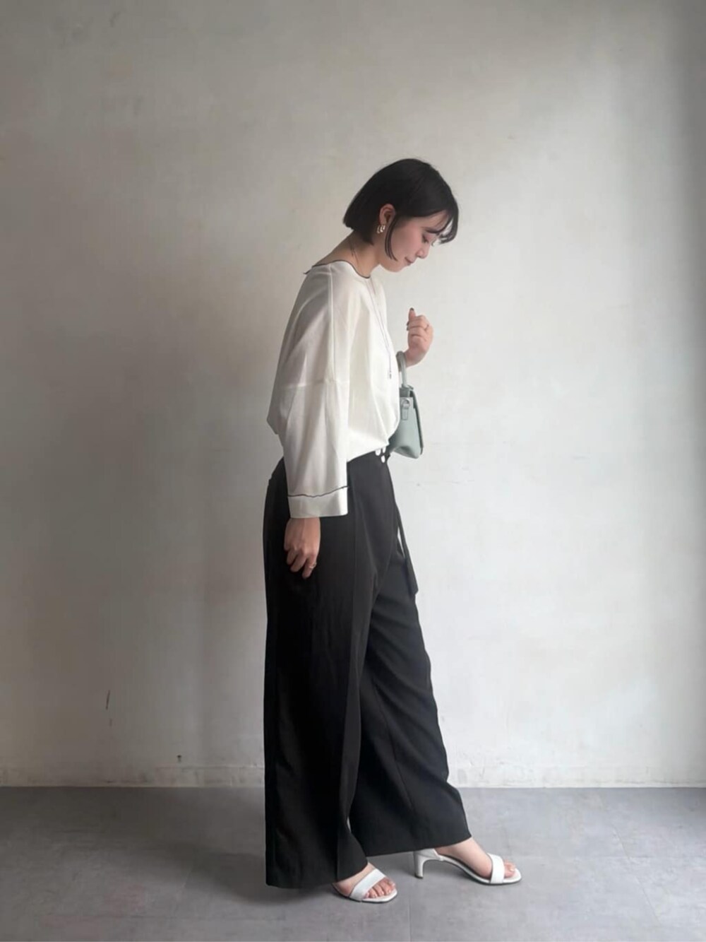 グリーン系のハンドバッグ、グレー系のその他パンツ、ホワイト系のTシャツ/カットソーを着用したレディースの冬コーディネートの5枚目の写真