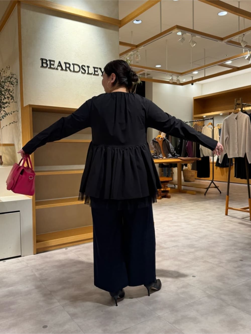 ピンク系のハンドバッグ、ブラック系のブーツ、ブラック系のブルゾンを着用したレディースの冬コーディネートの5枚目の写真