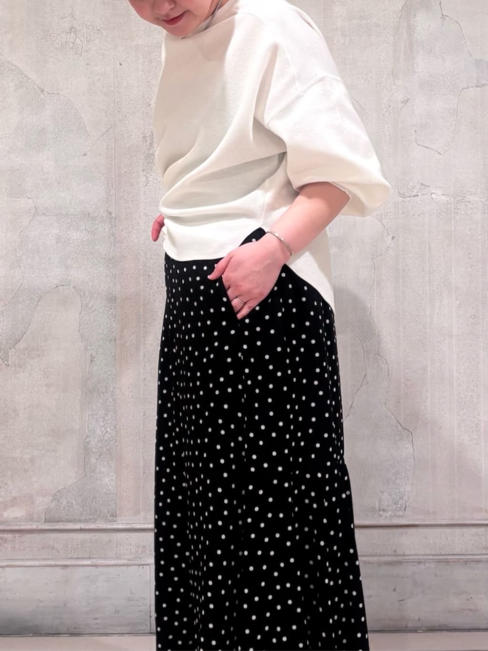 ブラック系のハンドバッグ、ブラック系のスカート、ホワイト系のTシャツ/カットソーを着用したレディースの春コーディネートの6枚目の写真