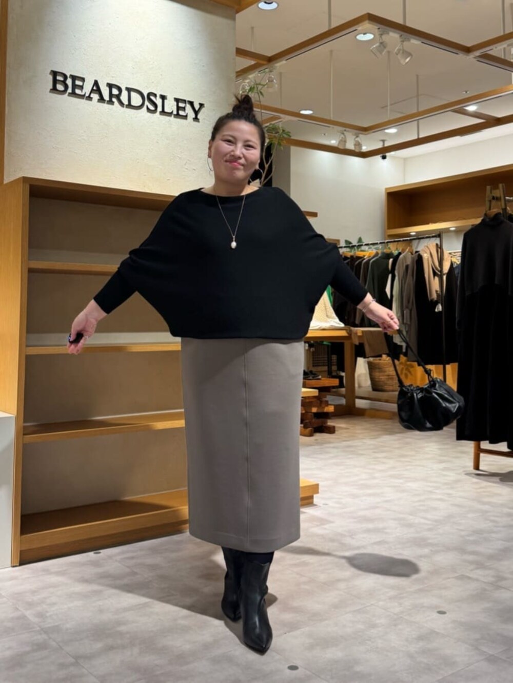 ブラック系のニット/セーター、ブラック系のブーツ、ブラウン系のスカートを着用したレディースの冬コーディネートの3枚目の写真