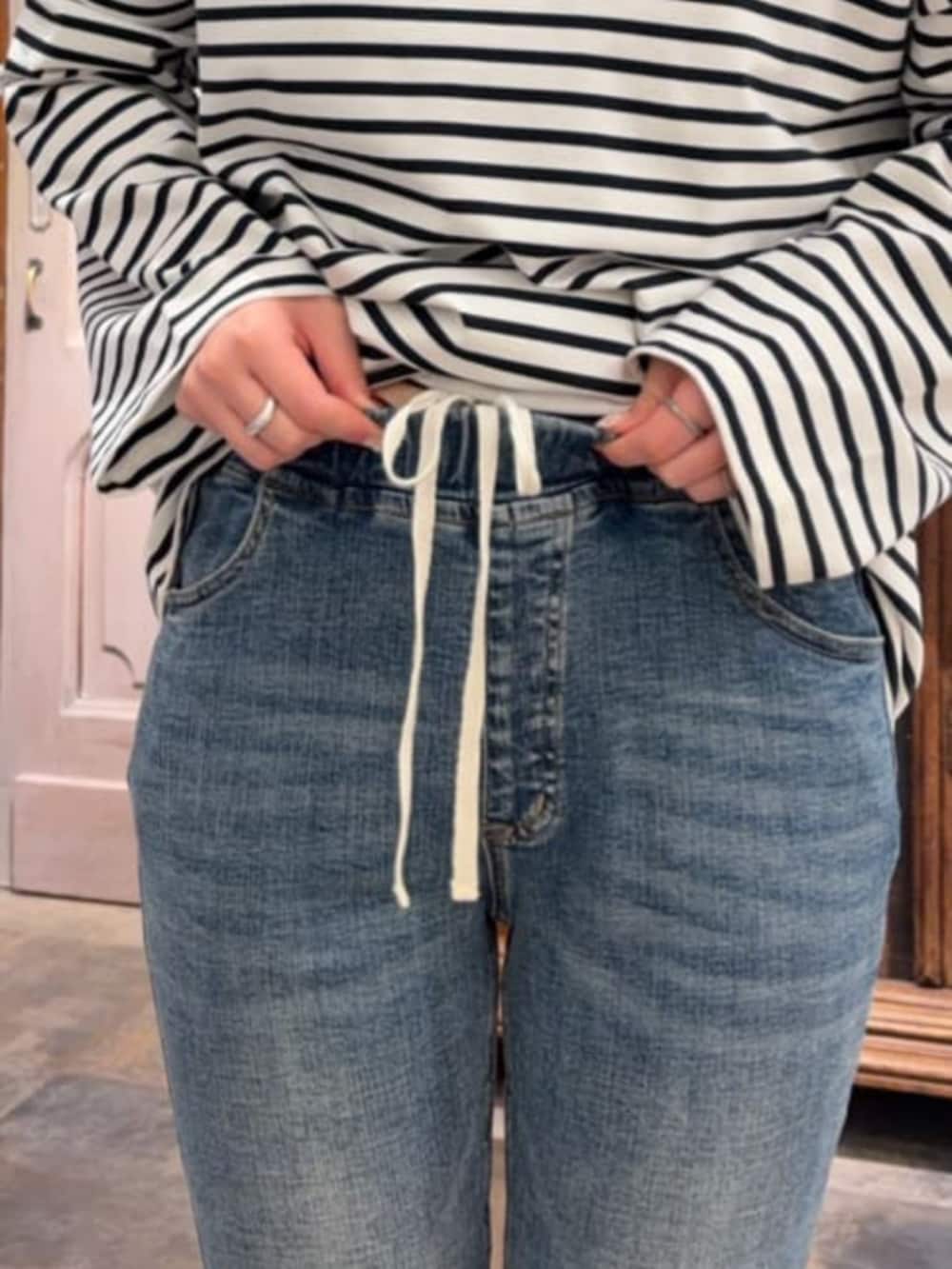 ブラック系のその他アウター、ブルー系のデニムパンツ、ブルー系のTシャツ/カットソーを着用したレディースの冬コーディネートの10枚目の写真