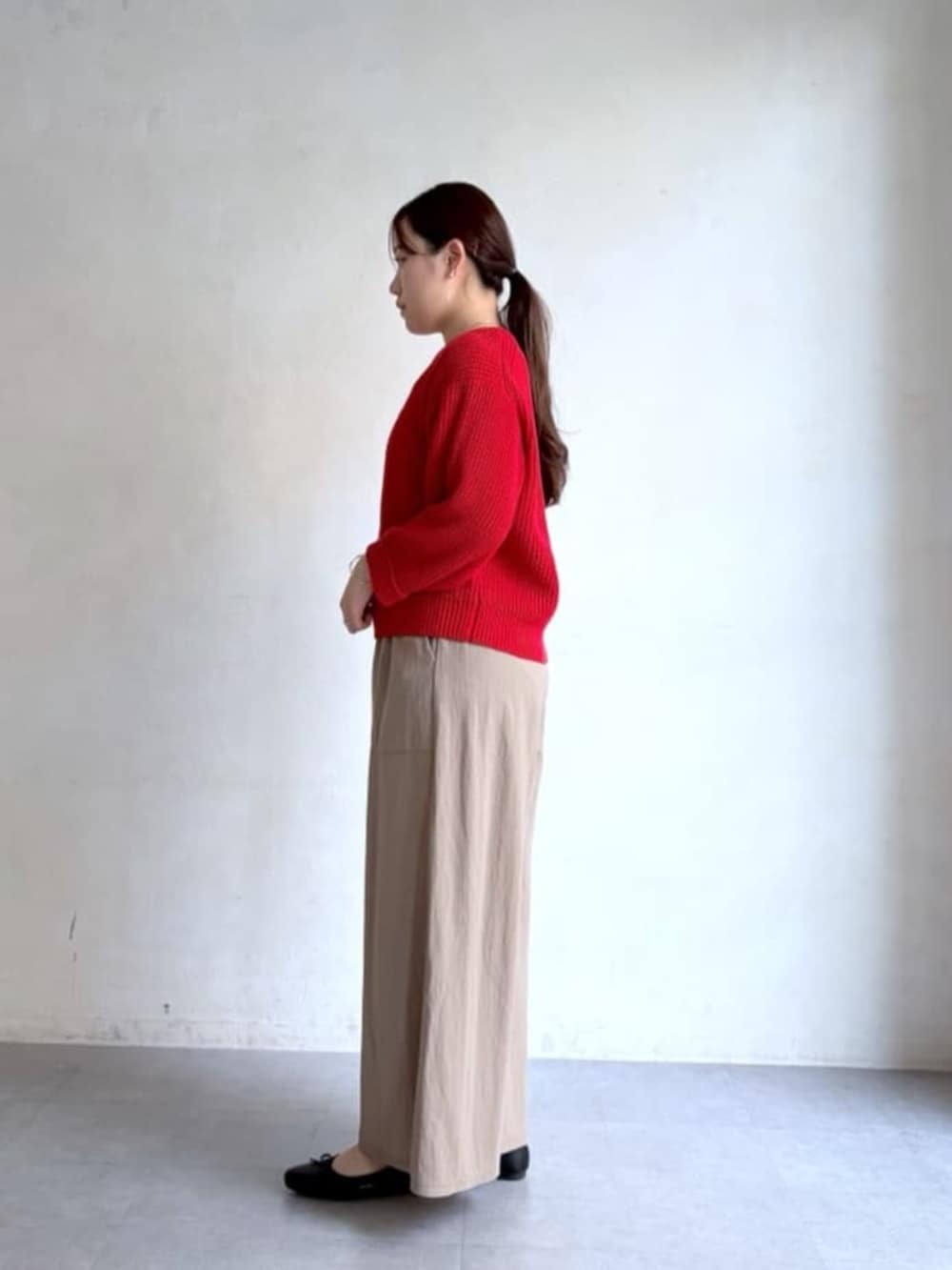 ベージュ系のその他パンツ、レッド系のニット/セーターを着用したレディースの冬コーディネートの2枚目の写真